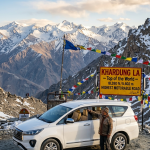 Innova Crysta rental Leh Ladakh 2026 - white Toyota Innova Crysta at Khardung La pass 18380 feet with premium captain seats