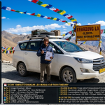 Ladakh tour package by car 2026 - white Innova SUV at Khardung La 18380 feet with Ladakhi driver giving thumbs up, prayer flags, snow-capped peaks, Leh Ladakh SUV tour 8 days ₹21,000-43,000 per person, Leh-Manali circuit 7 days ₹25,000-50,000, complete Srinagar-Leh-Manali circuit 12 days ₹38,000-85,000, Leh to Hanle and Umling La expedition 9 days ₹39,000-50,000, group size pricing for 12-day circuit ₹38,000-77,500 per person, group tour Srinagar to Leh 10 days ₹31,700, includes private SUV, driver, accommodation, meals, permits, oxygen