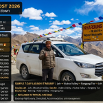 Ladakh trip cost 2026 - white SUV at Khardung La pass 18380 feet with Ladakhi driver giving thumbs up, prayer flags, budget trip ₹20,000-30,000 per person, mid-range trip ₹35,000-55,000, premium trip ₹60,000-1,00,000+, cost breakdown flights ₹12k-18k, accommodation ₹15k-25k, transport ₹5.5k-6k, food ₹5.6k-8.4k, permits ₹600-700, total mid-range ₹40k-58k, group savings solo ₹55k-80k, couple ₹40k-55k each, family of 4 ₹37.5k-55k each, group of 6 ₹35k-50k each, 7-day itinerary Leh Nubra Pangong, includes accommodation, meals, transport, permits, transfers