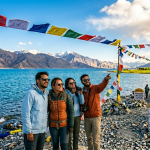 Leh Ladakh summer package 2026 - happy travelers at Pangong Lake with turquoise waters and snow-capped mountains