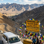 Leh to Nubra Valley cab package 2026 - white SUV taxi driving on Khardung La pass at 18380 feet world's highest motorable road with prayer flags