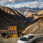 Leh to Nubra Valley via Khardung La taxi fare 2026 - white SUV taxi driving on Khardung La pass at 18380 feet world's highest motorable road with prayer flags