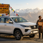Luxury SUV taxi Leh Ladakh 2026 - white Toyota Fortuner 4x4 at Khardung La pass 18380 feet world's highest motorable road with prayer flags