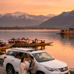 Luxury car rental for Kashmir honeymoon 2026 - newlywed couple with white Toyota Fortuner SUV overlooking Dal Lake at golden hour in Srinagar Kashmir