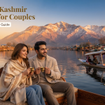 Romantic Kashmir packages for couples - couple on Dal Lake houseboat deck at golden hour with Shikara and Zabarwan mountains